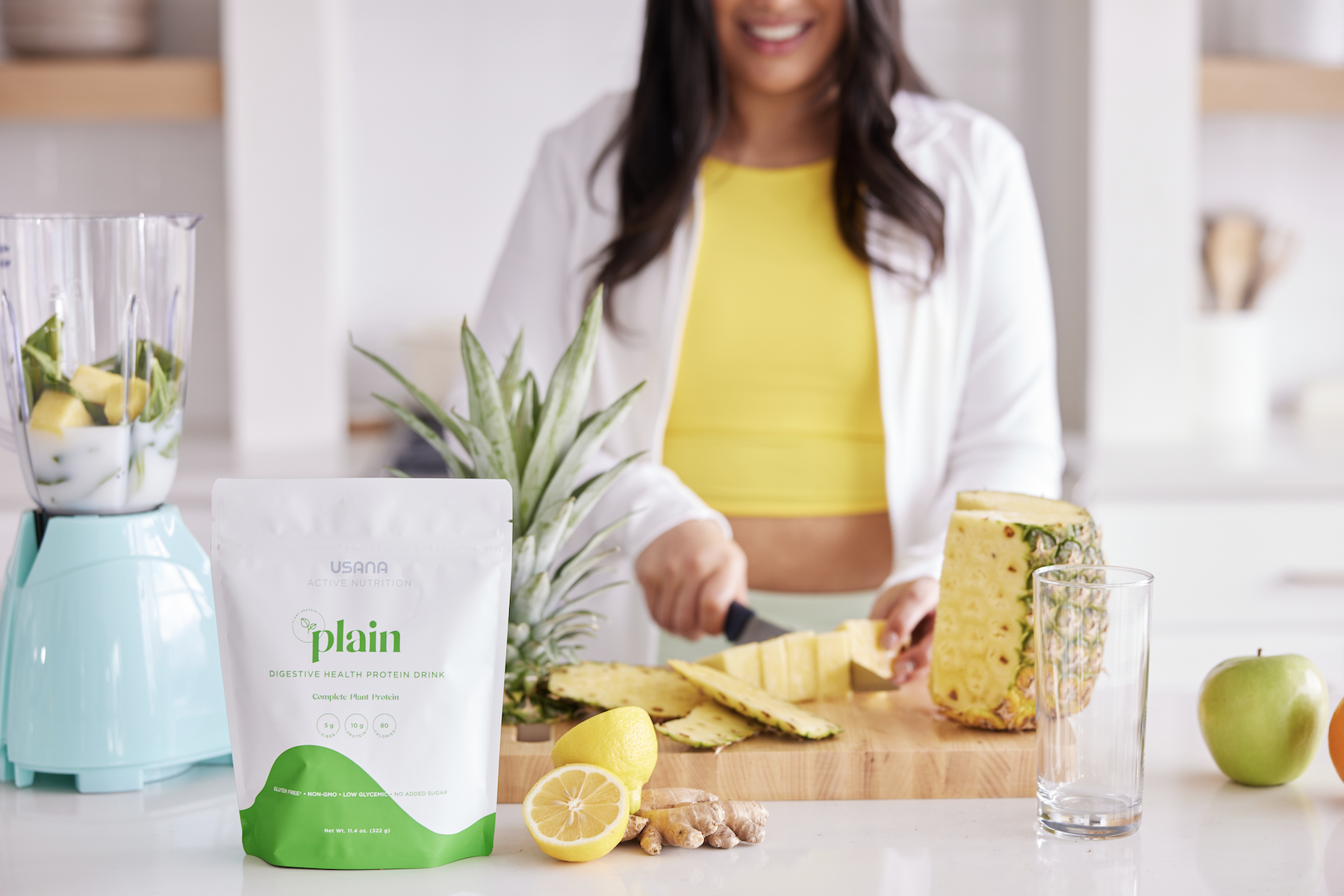 Woman preparing protein smoothie in ktichen slicing fresh pineapple